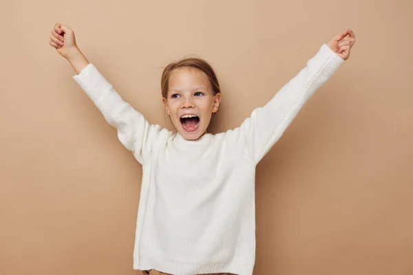 Portrét šťastného usmívajícího se dítěte dívka v bílém svetru pózuje gesta rukou dětství beze změny — Stock fotografie