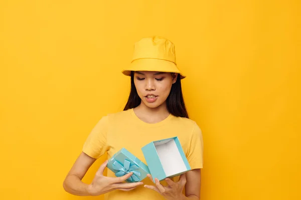 Charmig ung asiatisk kvinna blå presentask semester födelsedag gul bakgrund oförändrad — Stockfoto
