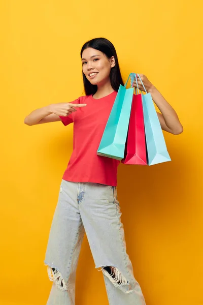 Mooie brunette met kleurrijke tassen poseren winkelen plezier gele achtergrond ongewijzigd — Stockfoto