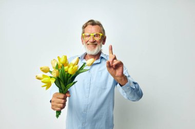 Yaşlı adam bir buket çiçek ve hediye olarak hafif bir arka plan.