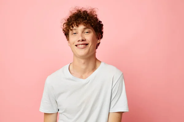 Portrait of a young curly man in white t-shirt casual wear emotions pink background unaltered — Stockfoto