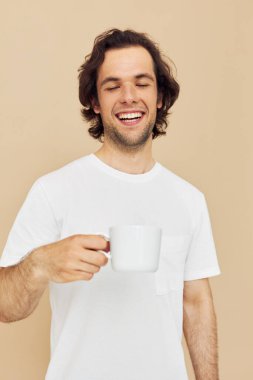 Elinde beyaz bir kupayla neşeli bir adam. Duyguları değişmemiş bir yaşam tarzı veriyor.