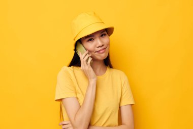 Çekici genç Asyalı kadın telefonda konuşuyor. Moda pozu veriyor. Geçmişi değişmemiş.