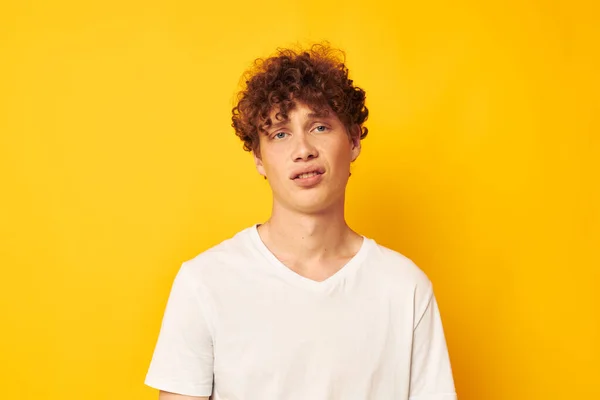 Tipo de pelo rojo rizado en una camiseta blanca sobre un fondo amarillo — Foto de Stock