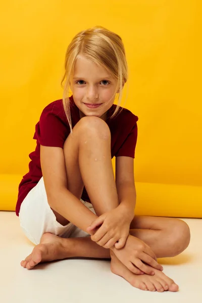 Küçük kız yerde oturuyor. Sarı arka plan duyguları. — Stok fotoğraf