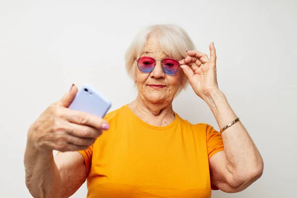 Retrato de una anciana amigable con una camiseta amarilla posando la comunicación por teléfono vista recortada — Foto de Stock