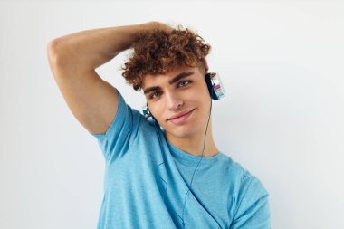 Mavi tişörtlü yakışıklı genç adam kulaklık takıyor. Yaşam tarzını değiştirmemiş.