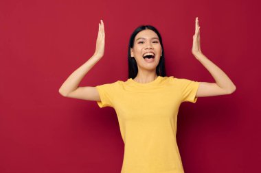 Çekici genç Asyalı kadın elleri sarı tişörtlü rahat giyiniyor stüdyo modeli değiştirilmemiş.