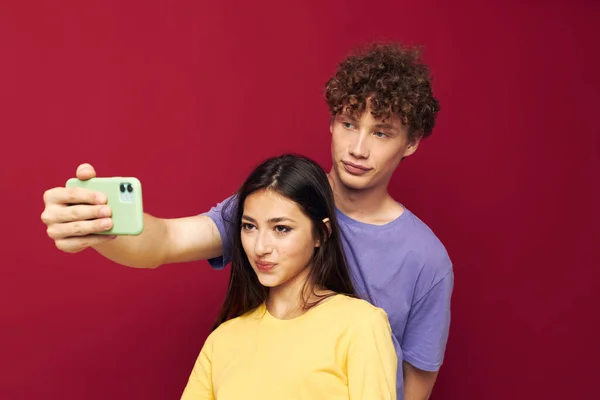 Una pareja joven estilo moderno emociones divertido teléfono rojo fondo — Foto de Stock