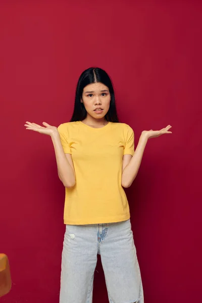 Retrato Asiático bela jovem gestos com as mãos em um amarelo t-shirt casual desgaste estúdio modelo inalterado — Fotografia de Stock