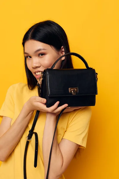 Bonito asiático menina posando fêmea embreagem saco amarelo fundo — Fotografia de Stock