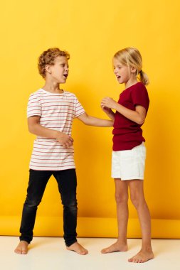 Pozitif erkek ve kızın renkli arka planda çocukluk eğlenceleriyle kucaklaşması.