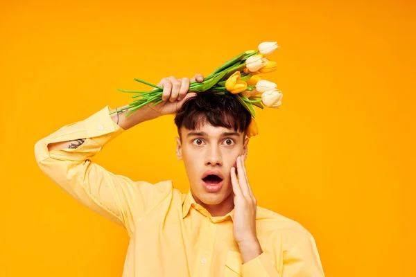 Chico guapo en gafas amarillas con un ramo de flores aislado fondo inalterado — Foto de Stock