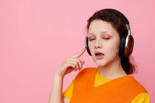 Όμορφη γυναίκα σε ένα πορτοκαλί πουλόβερ ακουστικά μουσική ψυχαγωγία ροζ φόντο αναλλοίωτη — Φωτογραφία Αρχείου