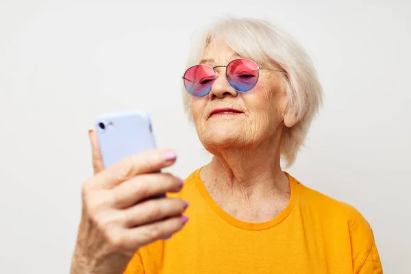 Anciana sonriente con una camiseta amarilla posando la comunicación por teléfono emociones de primer plano — Foto de Stock