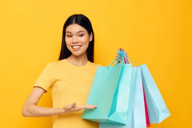 Sarı tişörtlü güzel esmer, çok renkli alışveriş çantalı stüdyo modeli değiştirilmemiş.
