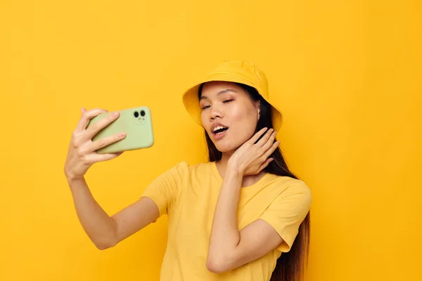 노란 모자와 티셔츠를 입은 아시아인의 아름다운 여성 이 아무런 변화 없이 전화로 이야기하는 모습 — 스톡 사진