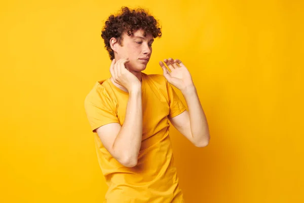 Joven rizado hombre amarillo camiseta moda mano gestos aislado fondo inalterado — Foto de Stock