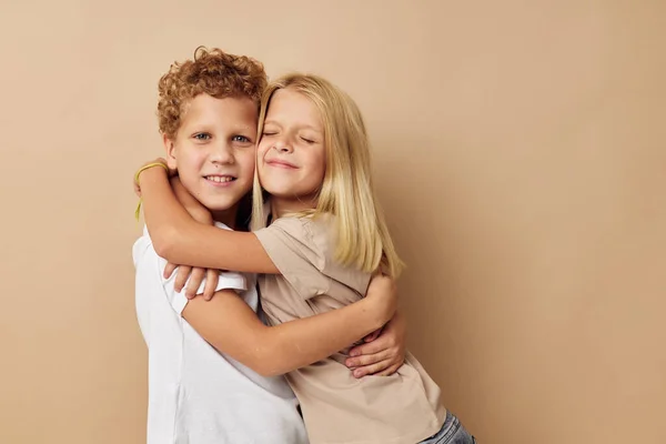 男の子と女の子でTシャツ抱擁ベージュ背景友情 — ストック写真