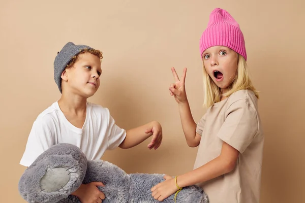 Мальчик и девочка в разноцветных шляпах развлечения представляя изолированный фон — стоковое фото