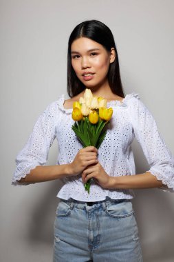 Bir buket çiçekle büyüleyici genç Asyalı kadın. Arka planda hiç değişmeden gülümse.