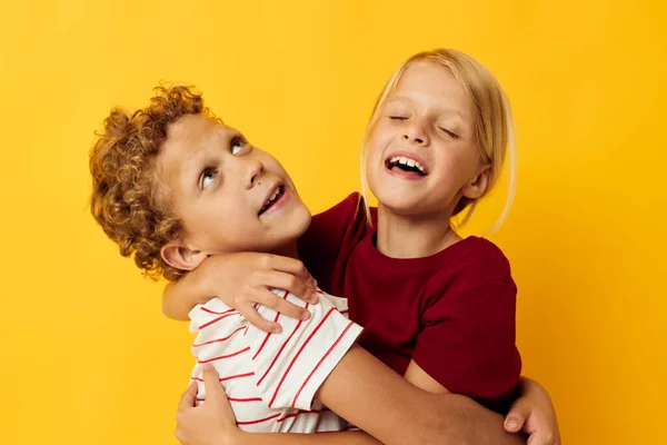 Весёлые дети стоят бок о бок, создавая детские эмоции, желтый фон — стоковое фото