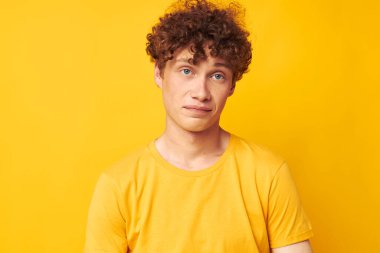 Genç, kıvırcık bir adamın portresi Gençlik tarzı gözlük stüdyosu gündelik sarı arka planı değiştirilmemiş