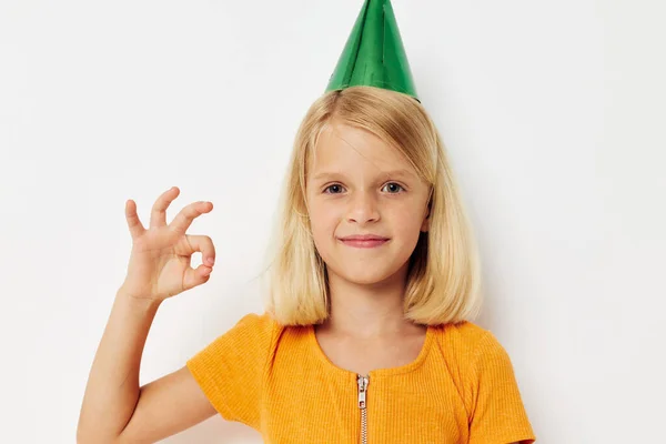 Uma menina com um boné verde na cabeça gestos com as mãos — Fotografia de Stock