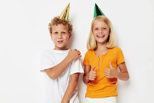 귀여운 아이들 이 변화가 없는 화려 한 배경의 다채 로운 휴일 모자를 쓰고 있다 — 스톡 사진