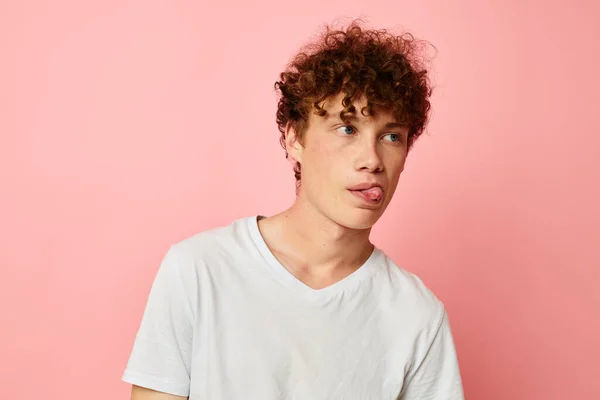 Retrato de un joven rizado hombre en camiseta blanca casual desgaste emociones rosa fondo inalterado — Foto de Stock