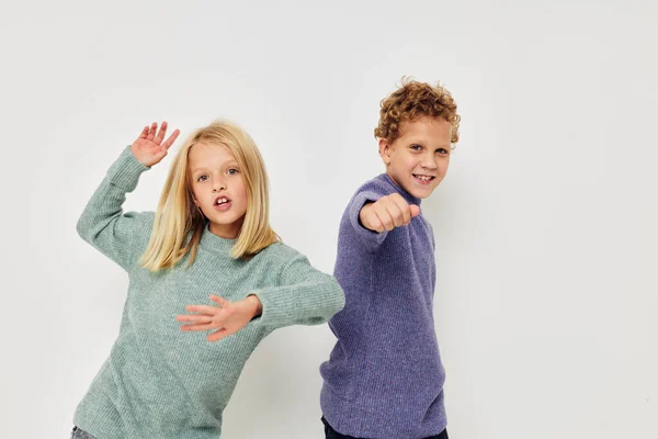 Portret uroczych dzieci w wielobarwnych swetrach pozujących dla zabawy lekkie tło — Zdjęcie stockowe