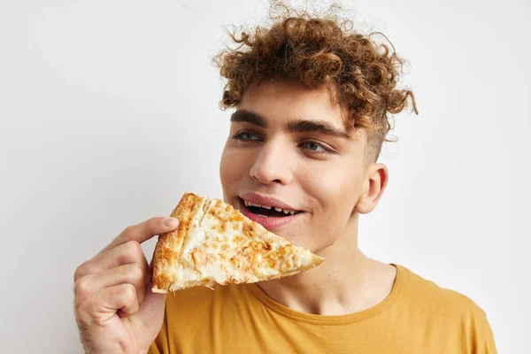 Guapo chico comer pizza posando primer plano luz fondo —  Fotos de Stock