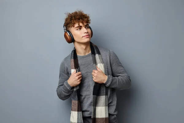 Przystojny młody człowiek elegancki styl w kratkę szalik słuchawki izolowane tło — Zdjęcie stockowe