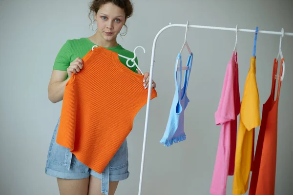 Mulher alegre experimentando roupas guarda-roupa estilo jovem luz fundo inalterado — Fotografia de Stock