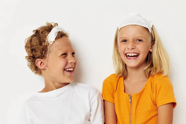 Two joyful children fun medical mask stand side by side close-up light background — Fotografia de Stock