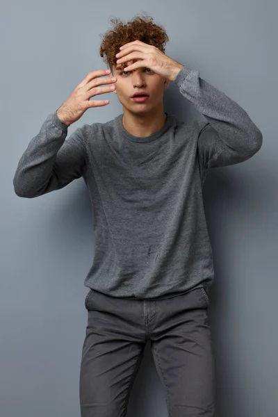 Atraktivní muž v šedé mikiny módní studio izolované pozadí — Stock fotografie