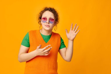 Neşeli kadın. Yüzünde çok renkli güneş gözlüğü var. Yüzünü buruşturuyor.