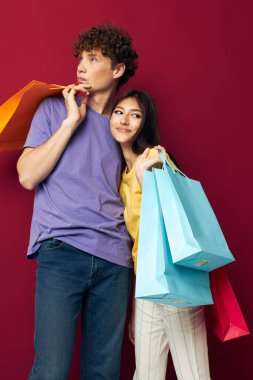 Bir erkek ve bir kadın alışveriş torbalarının portresi el değmemiş bir arka plan.