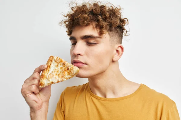 Привабливий чоловік у жовтій футболці, що їсть піцу Стиль життя незмінний — стокове фото