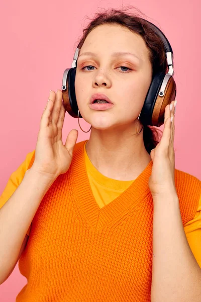 Retrato de uma jovem mulher ouvindo música com fones de ouvido laranja suéter emoções divertidas fundos isolados inalterados — Fotografia de Stock