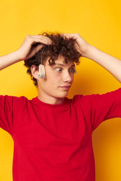 Portrait of a young curly man posing emotions tea bags isolated background unaltered — Stock Photo, Image