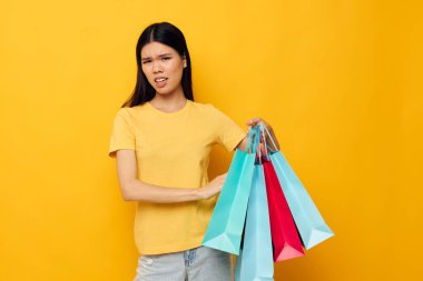 Sarı tişörtlü güzel esmer, çok renkli alışveriş çantalı stüdyo modeli değiştirilmemiş.