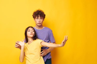 Genç erkek ve kız arkadaşlığı eğlenceli stüdyo sarı arka plan pozu veriyor.