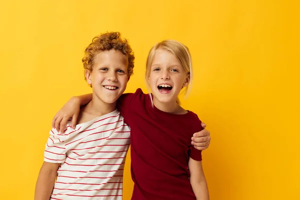 Picture of positive boy and girl standing side by side posing childhood emotions yellow background — 图库照片