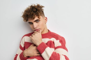 Çizgili süveter giyen çekici bir adam açık arka plan pozu veriyor.