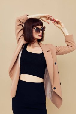 Bej ceketli, zarif güneş gözlüklü çekici bir kadın.