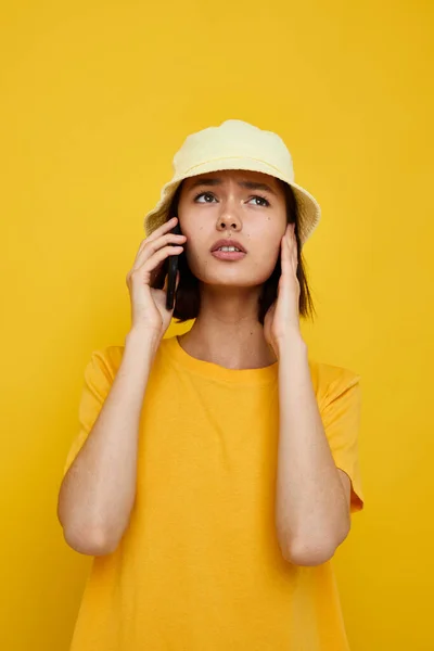 Jeune femme dans un chapeau jaune style jeune occasionnel parler au téléphone fond isolé — Photo