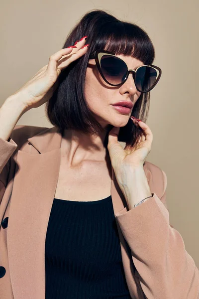 Foto bonita mujer en una chaqueta beige elegante estilo gafas de sol estilo de vida inalterado — Foto de Stock