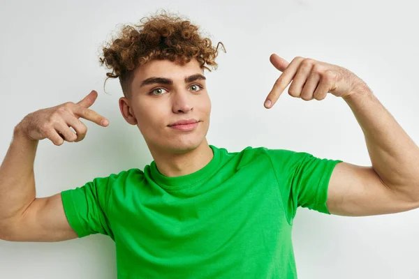 Bel ragazzo in verde t-shirt emozioni posa sfondo isolato — Foto Stock