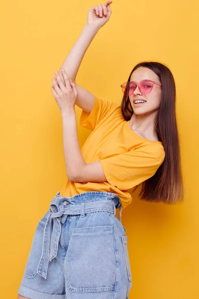 Moda mulher atraente em amarelo t-shirt calções de ganga fundo amarelo — Fotografia de Stock